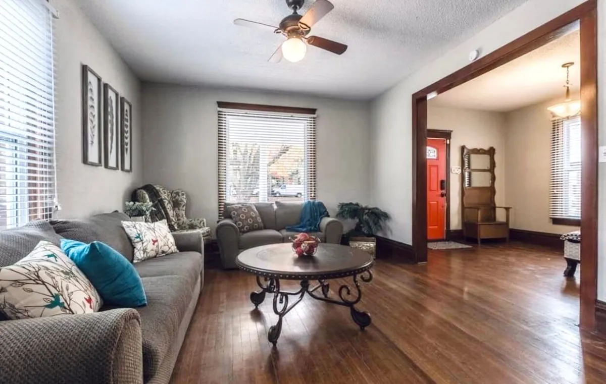 A cozy living room scene with a sofa and coffee table set near a window. The space is comfortable and bright, offering a relaxed yet attentive atmosphere suitable for focused tasks or virtual meetings.