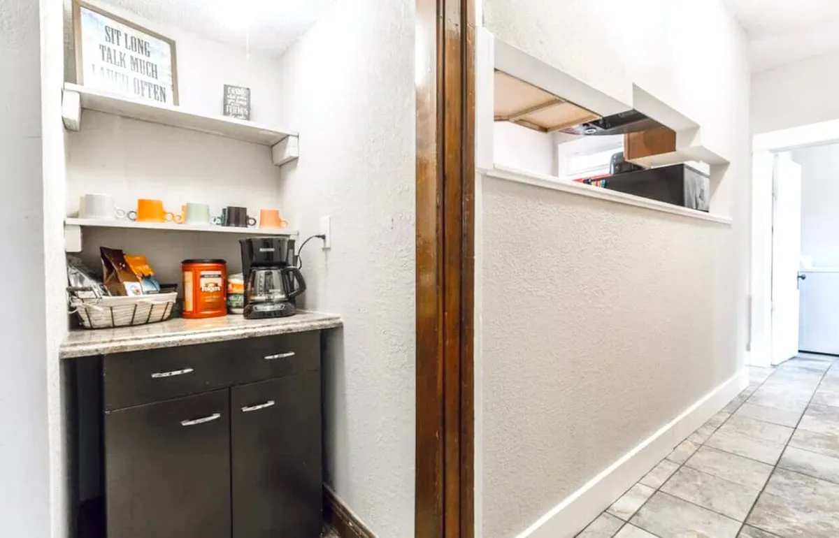 A kitchen corner with a coffee maker, colorful mugs, and granite countertops, exuding a welcoming vibe. The scene suggests a quick morning coffee before heading out to the city's attractions or a relaxing chat after an eventful day.