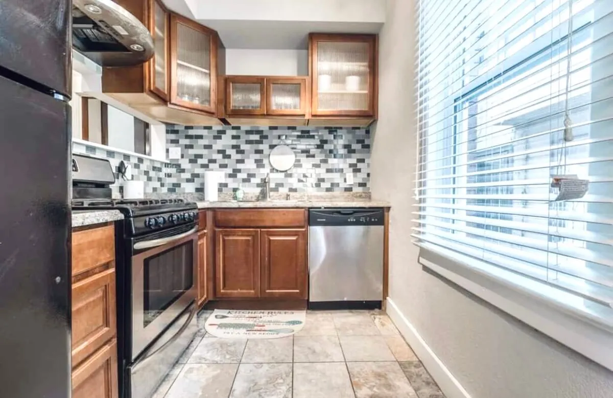 A modern kitchen outfitted with granite countertops, stainless steel appliances, glass-front cabinets, and a decorative backsplash. The space is set up for everything from casual breakfasts to larger gatherings, with an open, welcoming ambiance.